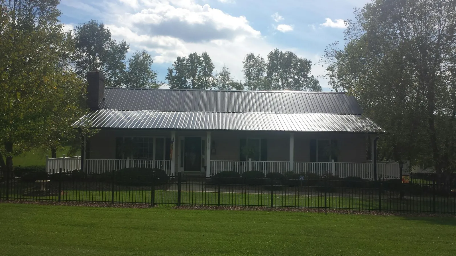 Gray metal roof on a brick ranch with a full width front porch — Gutter Guard Installation work by our crew in Stanford